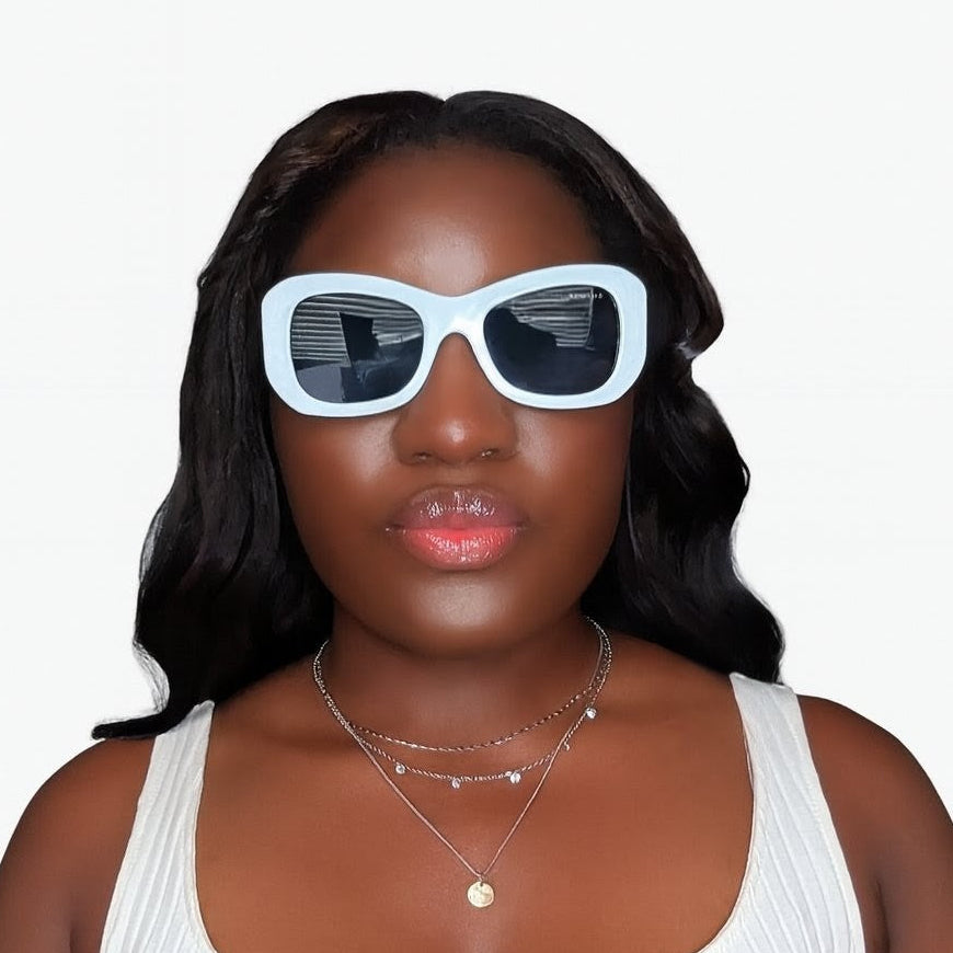 Woman wearing white sunglasses with black lenses on a plain background